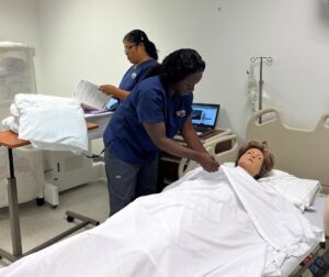 Student tending to SIM patient in a hospital bed. 