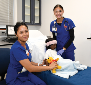 Two Nursing students administering care to a child mannequin.